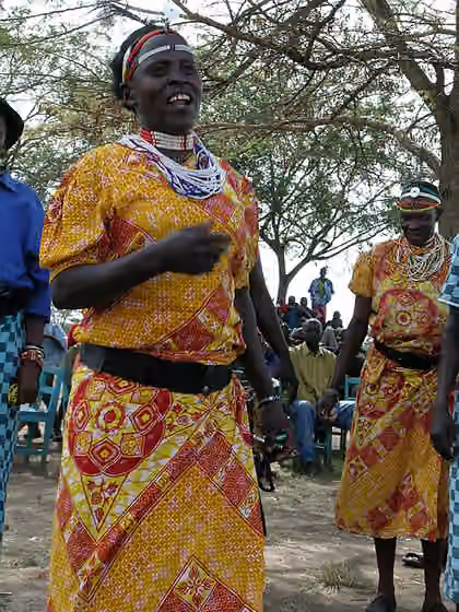 Kuria people — Two Kuria men dressed in yellow and red robes and beads dancing and singing.