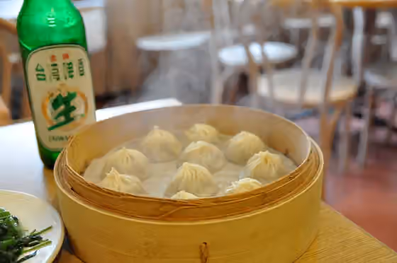 Masakan Taiwan — 餐桌上的小籠包、炒空心菜與一瓶金牌台灣啤酒,在台北一家鼎泰豐餐廳內