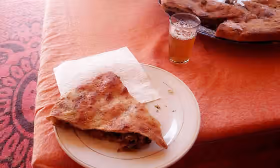Medfouna — Medfouna or Berber Pizza served a glass of Moroccan mint tea at a local restaurant near Merzouga, Errachidia, Morocco