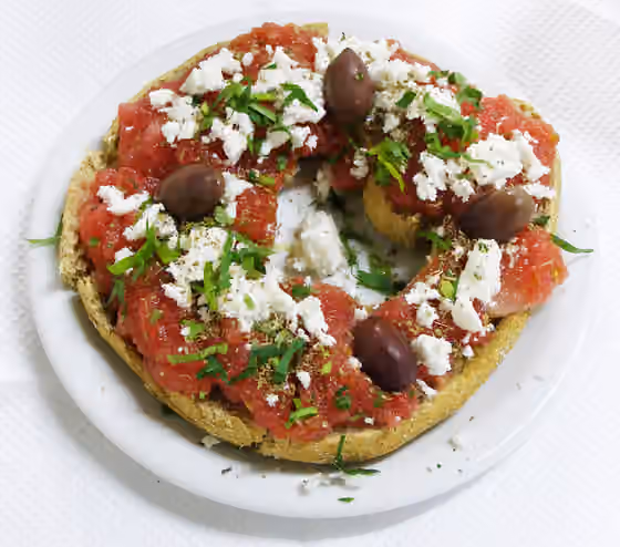 Dakos — Greek Food called Koukouvagia ("owl"), a dried bread made from barley with oil, tomato, cheese, oregano and olives, the way it is made in "Taverna Myrthios" in Myrthios , Crete