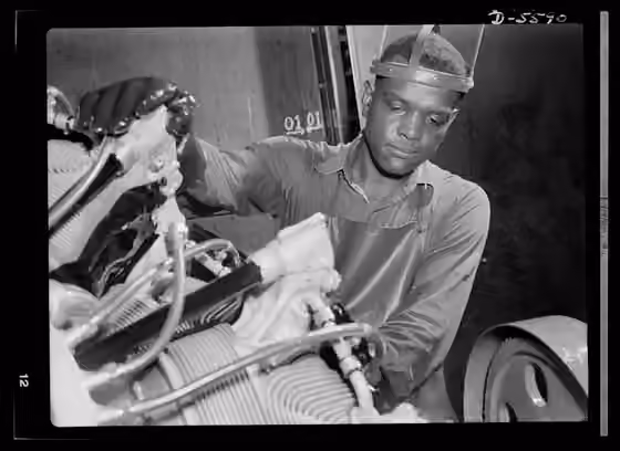 African Americans in Illinois — A young Negro worker stands ready to wash or "degrease" this airplane motor prior to its shipment.