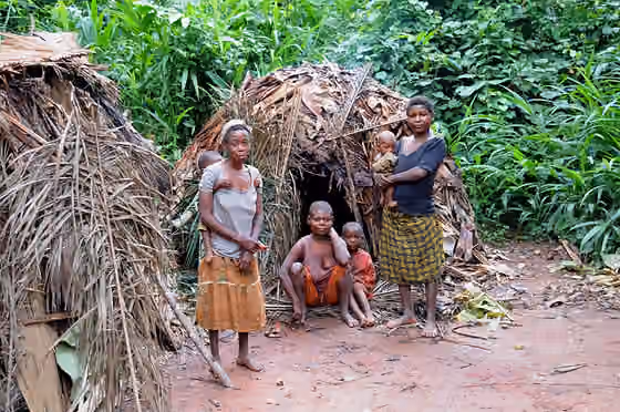Suku Aka — A BaAka (Aka) family standing in front of their traditional temporary forest huts in Dzanga-Sangha National Park, Central African Republic.