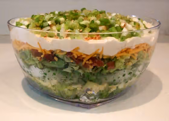 Seven-layer salad — Seven-layer salad is an American dish that includes a colorful combination of seven layers of ingredients: iceberg lettuce, tomatoes, cucumbers, onions, sweet peas, hard boiled eggs, sharp cheddar cheese, and bacon pieces.The salad is…