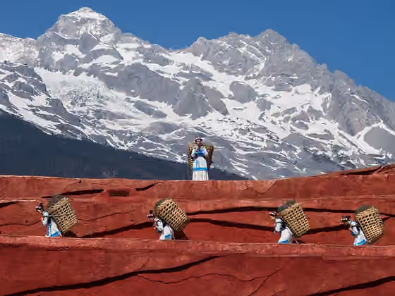 Suku Nakhi — Lijiang, Yunnan, China: Nakhi people carrying the typical baskets of the region; scene from a public perfomance in Jade Dragon Snow Mountain Open Air Theatre.