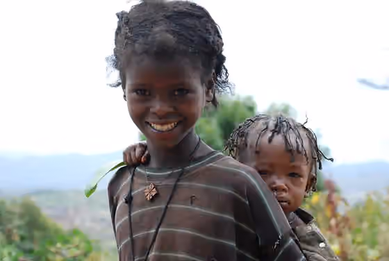 Orang Konso — Konso girl carrying her younger sibling in a traditional Konso village, Ethiopia.