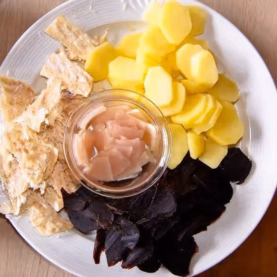 Faroese cuisine — Tvøst og spik -- pilot whale meat (black) and blubber (middle) and dried fish (left) and potatoes, a traditional meal on the Faroe Islands.