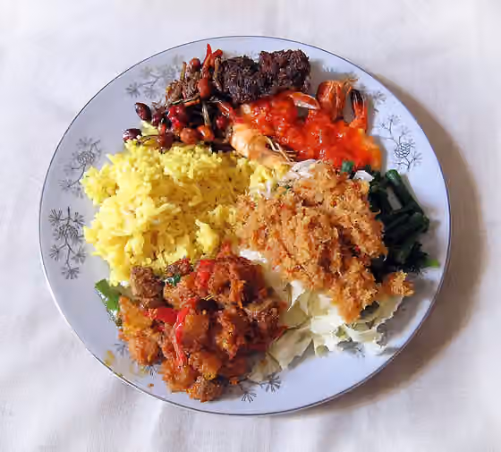 Nasi kuning (Indonesia) — Delicious and succulent Nasi Kuning Ibu Sulastri, yellow rice colored with turmeric, surrounded by teri kacang (anchovy with peanuts), empal gepuk (sweet fried beef), udang balado (shrimp in chilli), urab (vegetables in shredded coconut…
