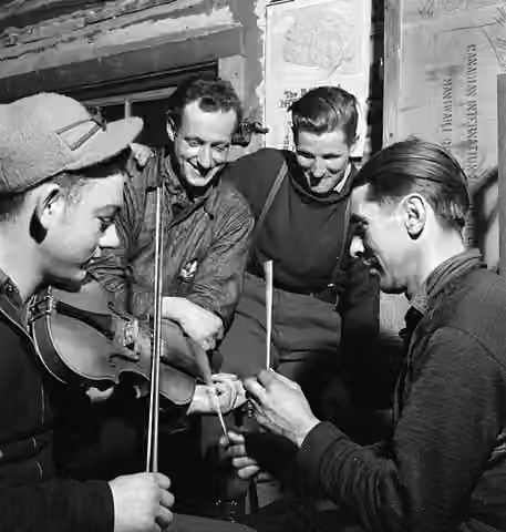 French-Canadian music — Lumbermen of Quebec playing a violin and using sticks to make music in their lumber camp.