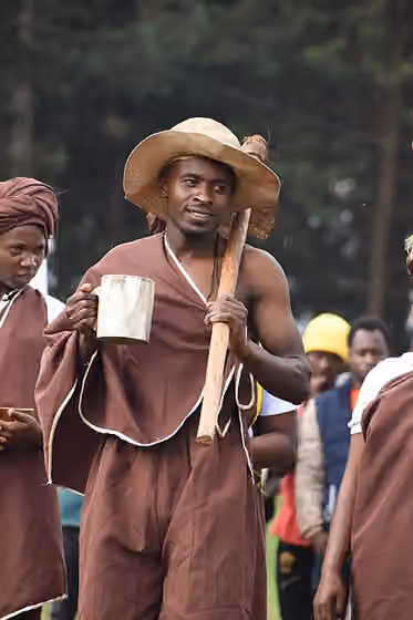 Kiga people — Fully dressed mukiga man in Bakiga traditional attire with a hoe and a wooden cup full of Bushera showcasing the rich culture of people from Kigezi in Uganda.