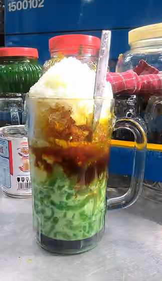 Cendol — A glass of Es Cendol consists of (from bottom) cendol green jelly in coconut milk, liquid gula jawa (palm sugar), tapai singkong (fermented sweet cassava), shaved ice and sweetened condensed milk.