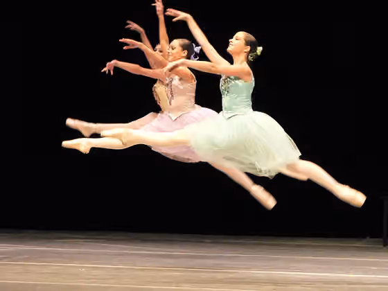 Tarian konser — Three ballet dancers performing a grand jeté jump