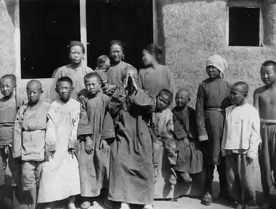orang Manchu — 撮影地点不明.当時写真撮影の困難のひとつは,人々が写真を恐れて逃げ出してしまうことにあった.この老人はカメラの前に立たされて,思わず拝んでしまった.さぞかし恐ろしかったことだろう.