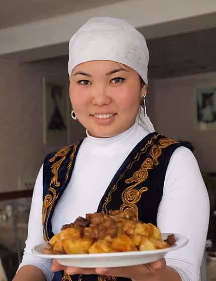 Masakan Kirgizstan — A Kyrgyz woman in national costume with dish.