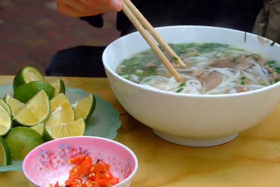 Masakan Vietnam — A steaming bowl of phở bò (rice noodle soup with beef) and its condiments, as served in the Cầu Giấy district , Hanoi.