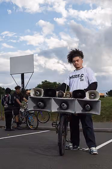 Siren kings — Mischief.C / Mizgf.C, a siren king and siren beat producer, standing in front of his modified bicycle used in siren battles.