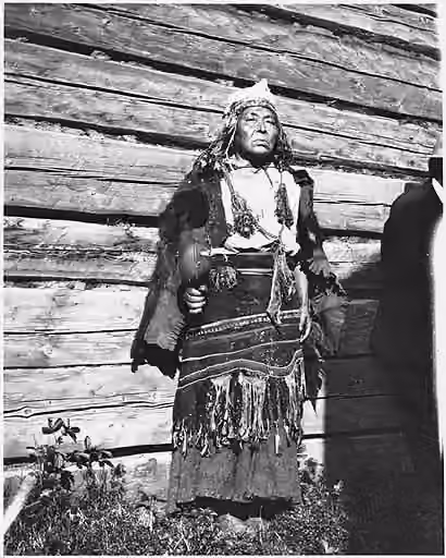 Shamanic music — Item Title Gitksan woman Shaman and Chief, Kispiox, British Columbia, 1909 Created/Published 1909 Notes Man poses outside by wall, with hide cloak, woven fabric wrapped about waist, headdess with decorations; he holds large rattle.