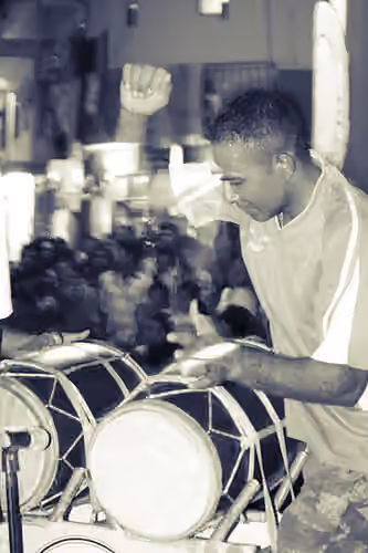 Boduberu — A drummer playing the boduberu while people watch in the background