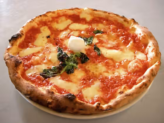 Masakan Italia — Picture of an authentic Neapolitan Pizza Margherita taken by Valerio Capello on September 6th 2005 in a pizzeria ("I Decumani") located on the Via dei Tribunali in Naples .