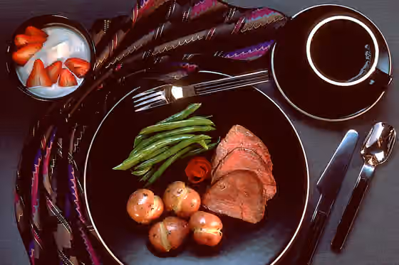 Roast beef — A dinner is set up on black, gold-rimmed dishes on a black tabletop.