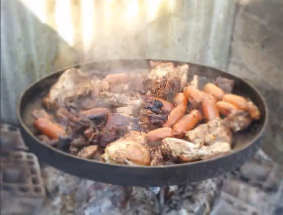 Discada — mixture of meats and seafood cooked in white wine and covered with sheets ready for cooking vegetables on a platter with coal iron
