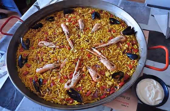 Fideuà — Una paella de fideuá, con alioli como complemento.