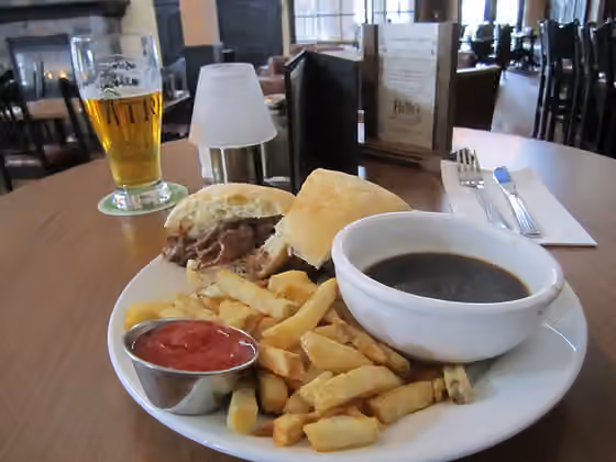French dip — Roast beef dip, french fries, au jus, ketchup, beer and fire in background