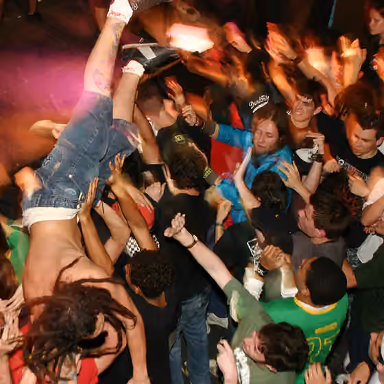 Moshing — A man crowd surfing in a mosh pit, uploaded from Flickr