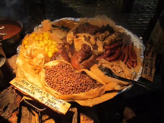 Latvian cuisine — Latvian food at the Christmas market in Dome Square: baked potatoes, pork ribs, stewed cabbage, duck leg, grey peas with bacon, pig's leg, ear and snout, grilled pork on a stick, grilled chicken on a stick, sausages, black pudding, rolled…