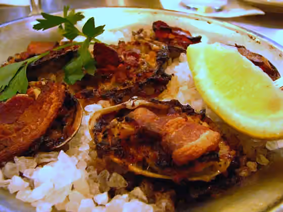 Cuisine of New England — A Clams casino over rock salt with lemon and parsley garnish.